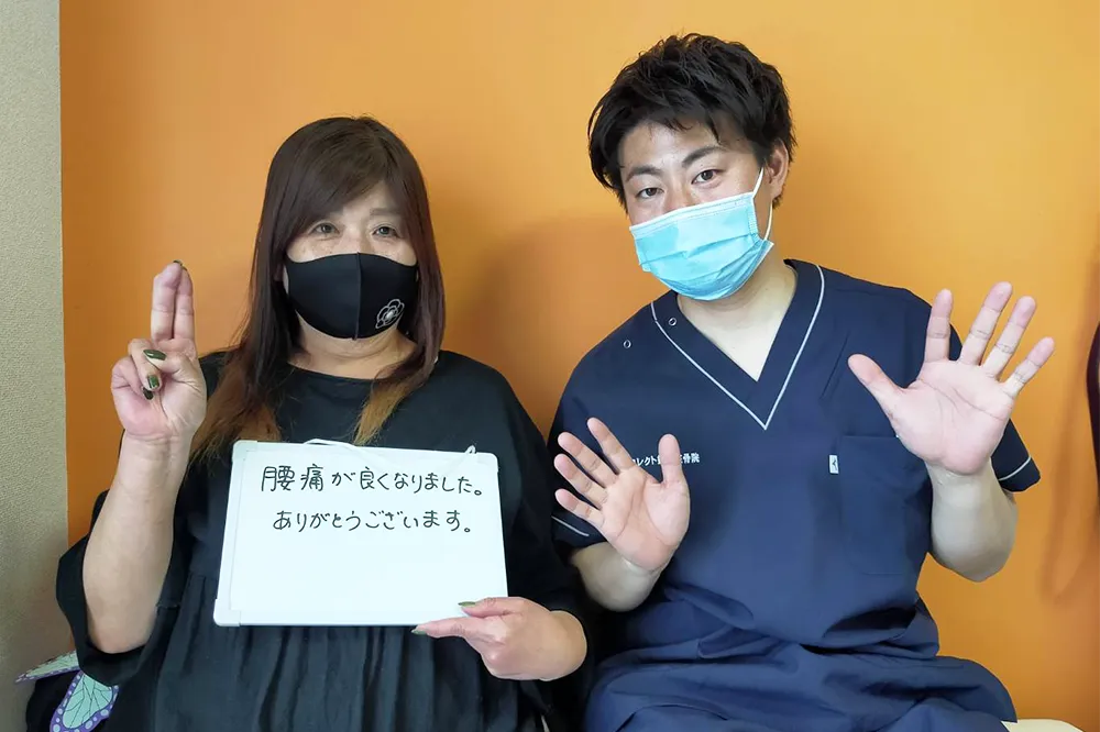 症状が改善した患者と並ぶ整体師