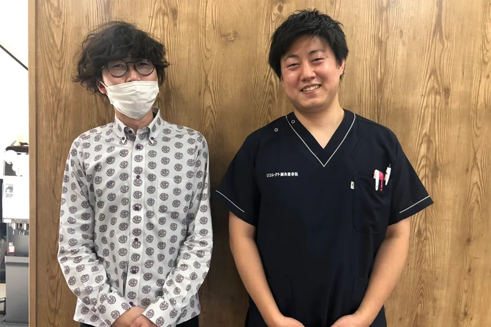 症状が改善した患者と並ぶ整体師